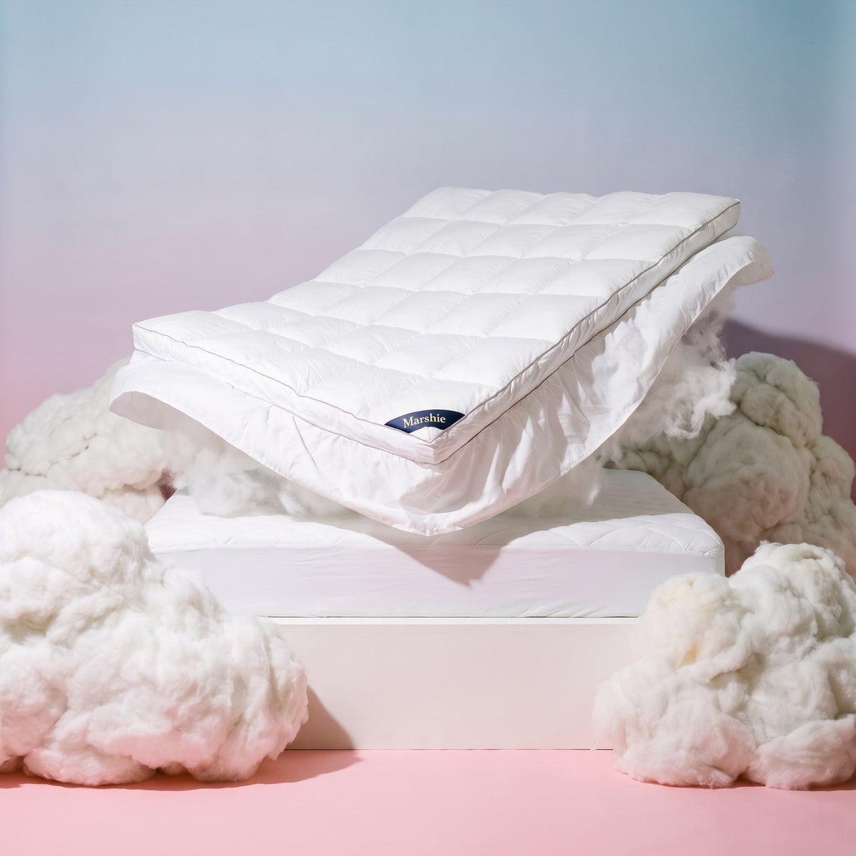 The Marshie Topper floating above a mattress between white clouds